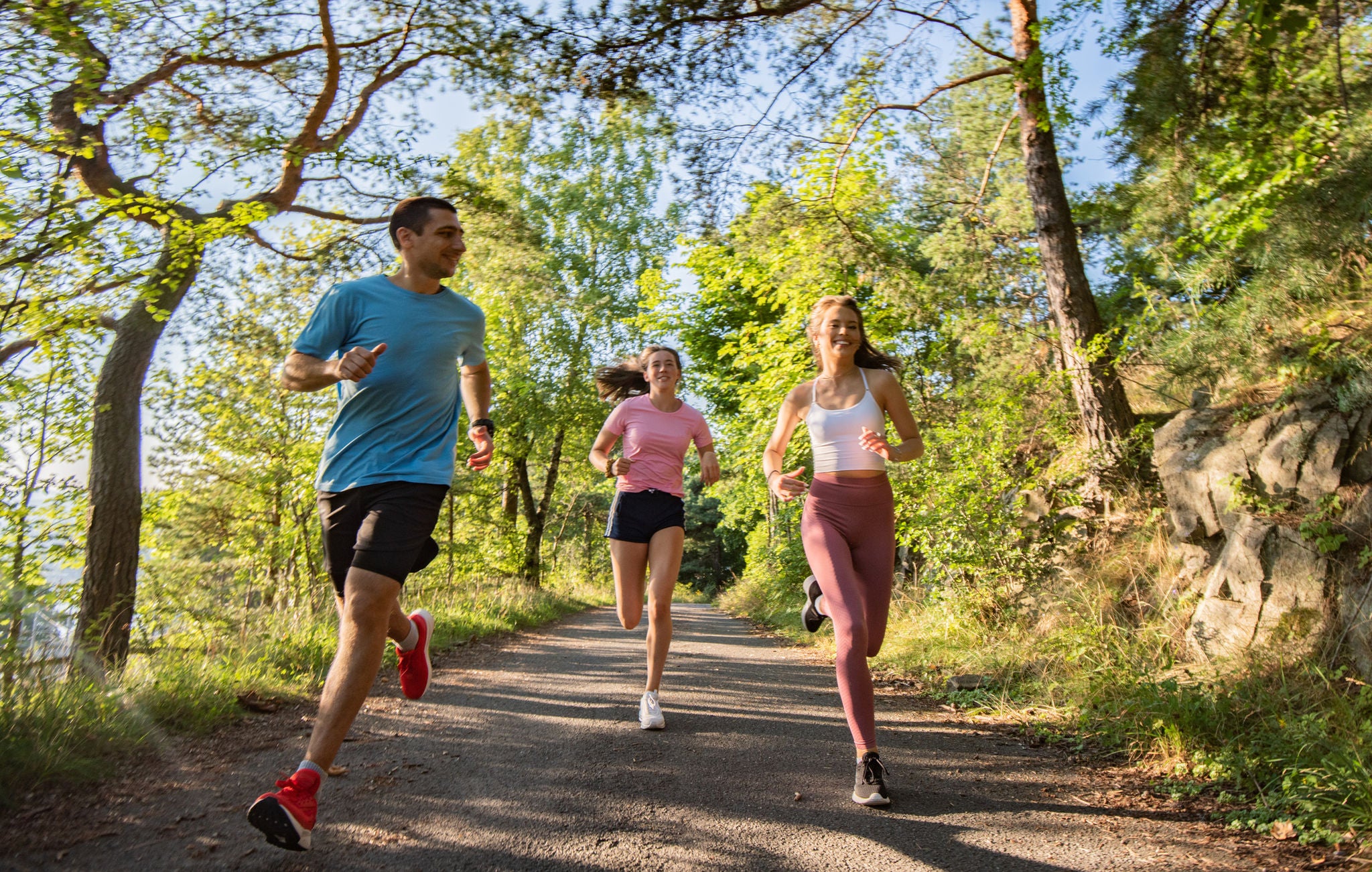 Three happy friends running in public park.